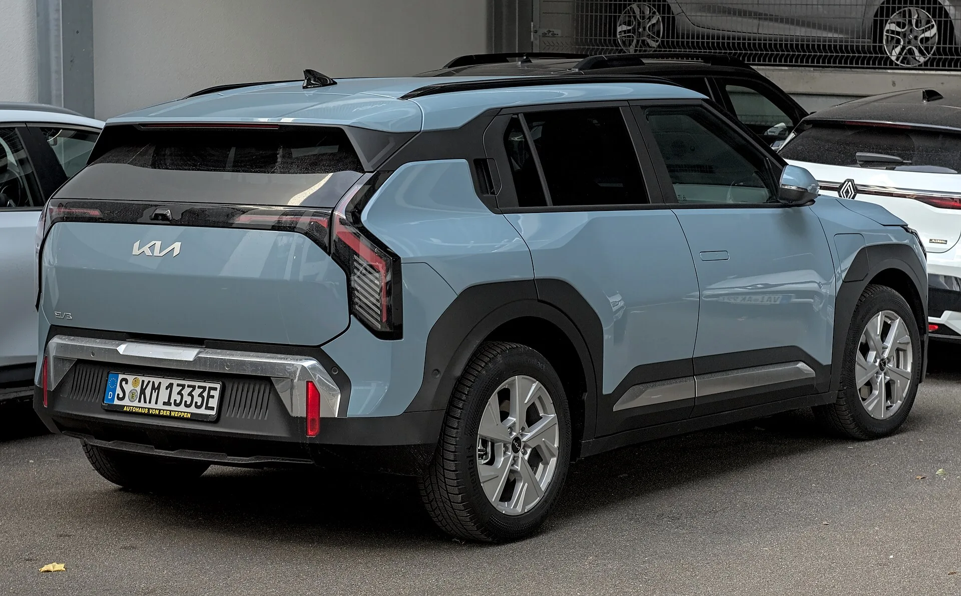 Açık mavi renkli Kia EV3 elektrikli SUV'un arkadan ve yandan görünümü