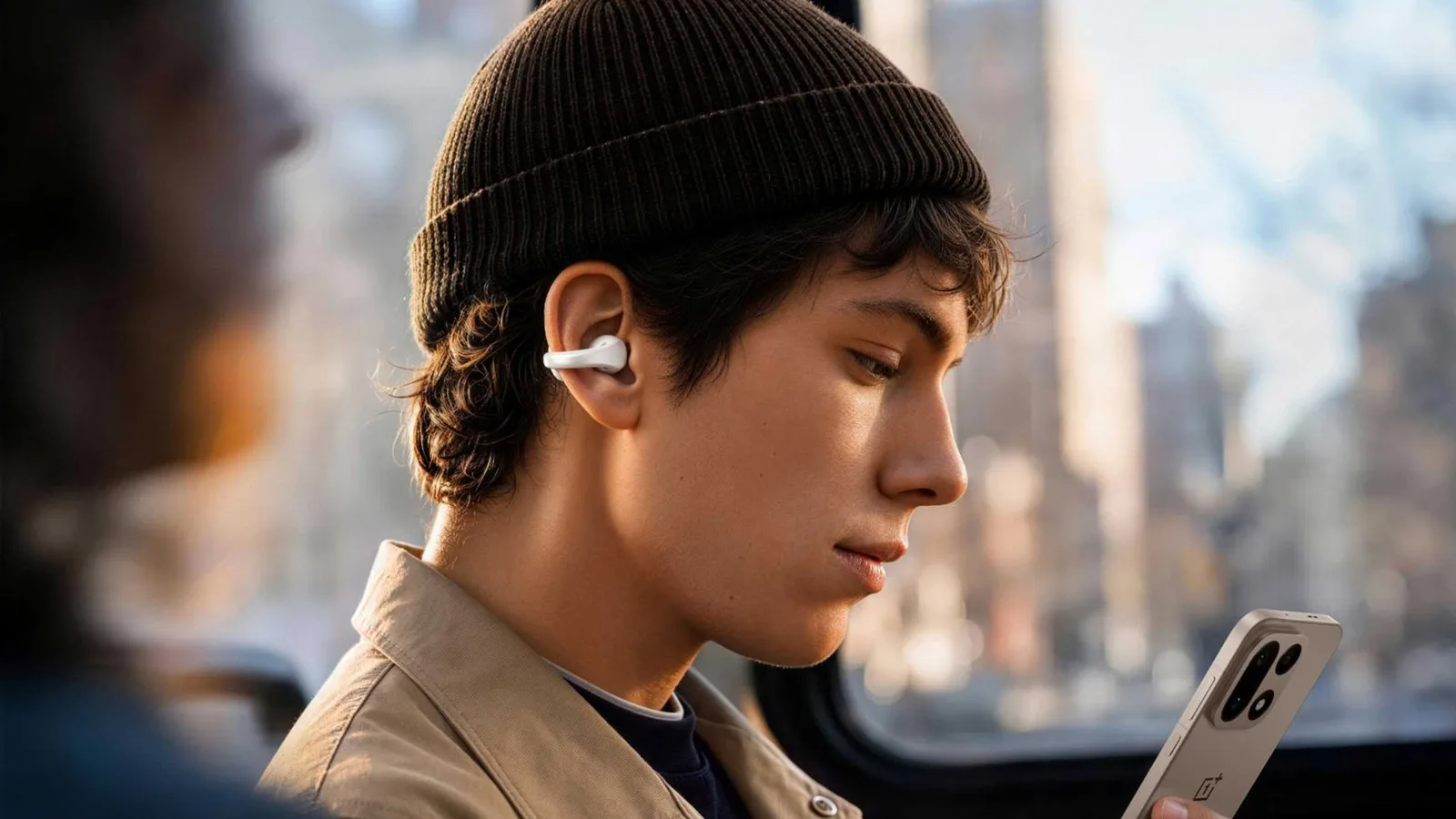OnePlus Buds Clip kulaklığı takan, telefona bakan genç adam