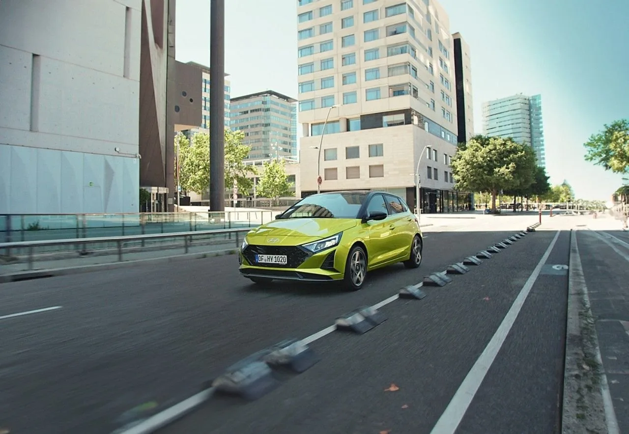 Sarı Hyundai i20 şehir içinde bir yolda ilerliyor, arka planda yüksek binalar