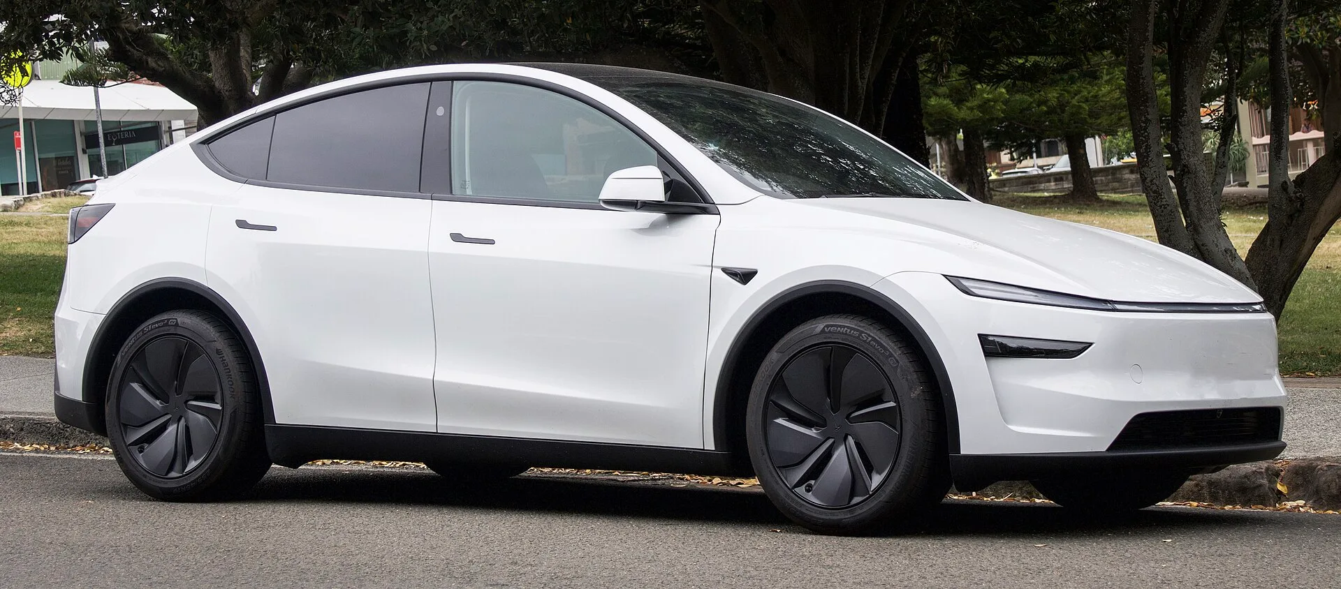 Beyaz renkli 2025 Tesla Model Y'nin yandan ve önden görünümü