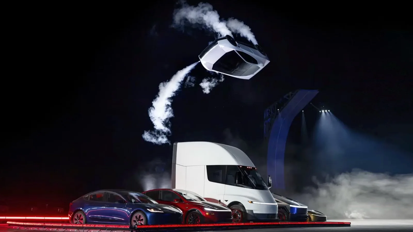 Tesla Roadster soğuk gaz iticileriyle havada takla atarken; altında Model 3, Model Y, Semi ve Cybertruck dizili
