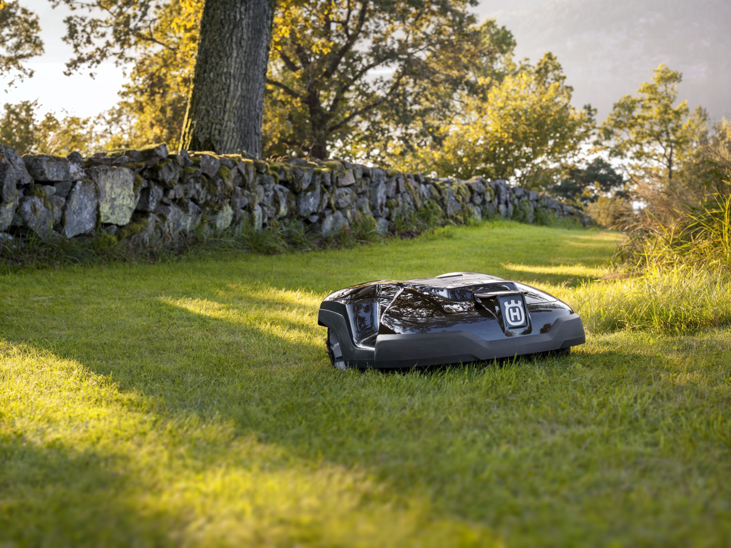 Futuristic garden scene with Husqvarna Automower 405XE NERA and 305E NERA cutting grass in a vibrant landscape.